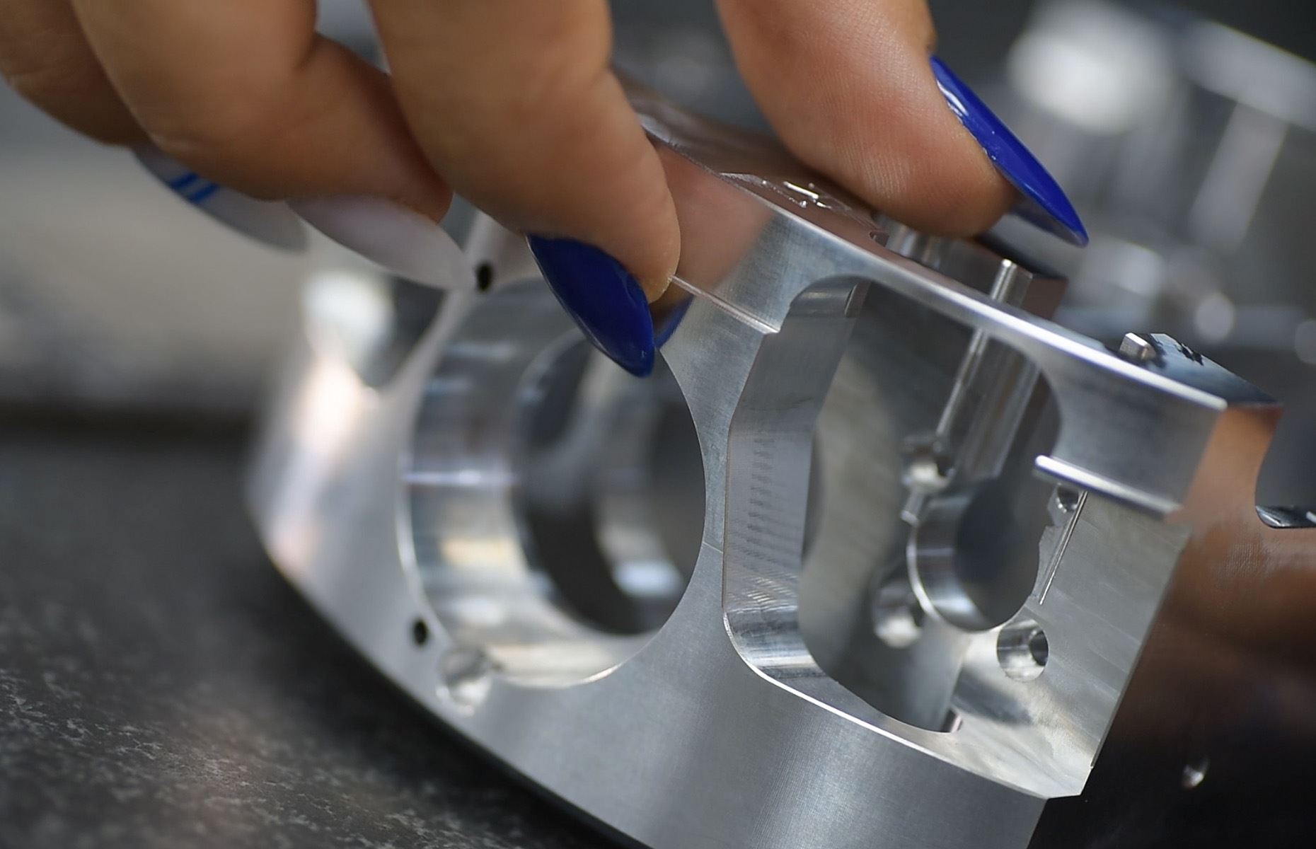Inspector checking a machined aluminum bracket by hand