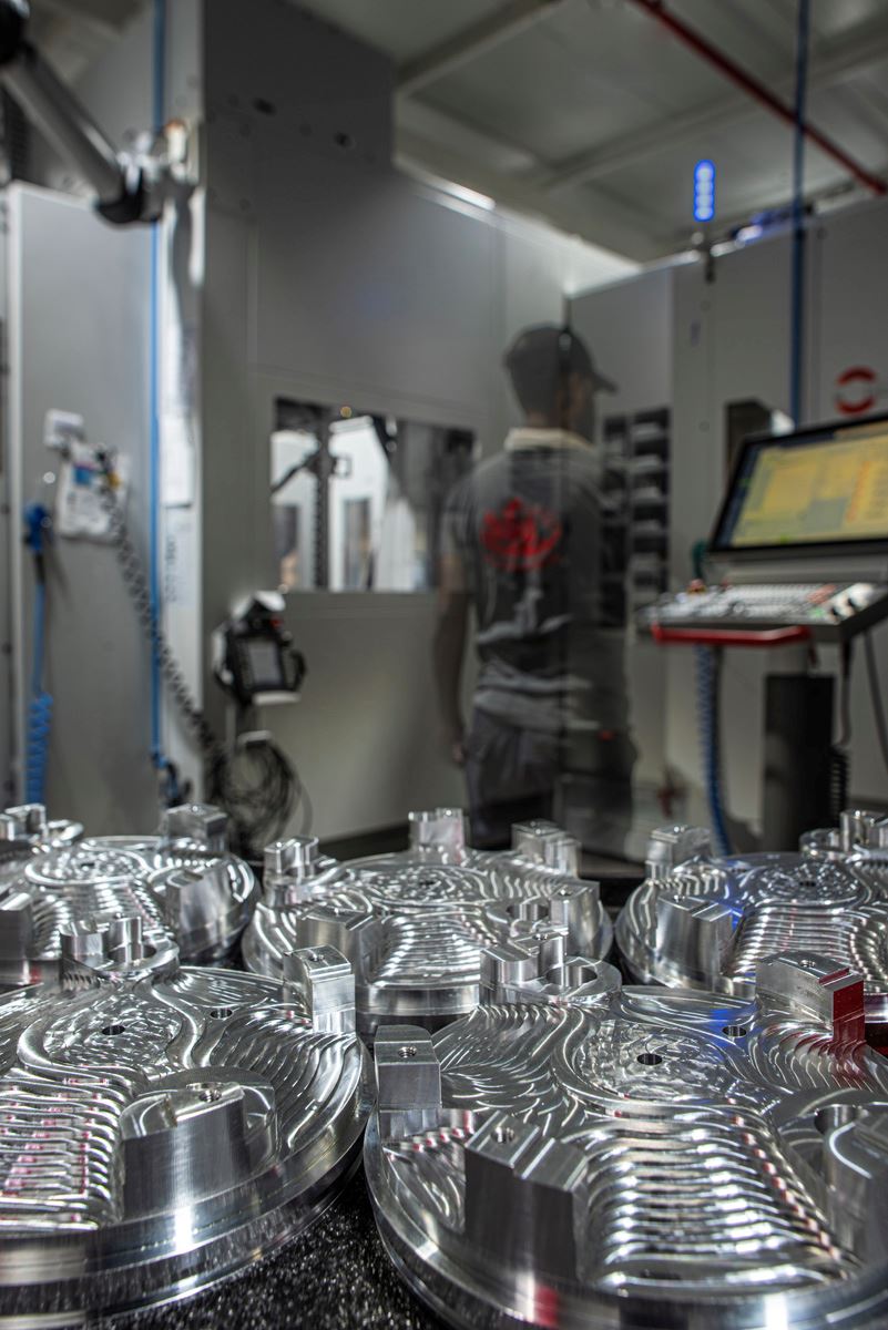 Machined round parts with operator at CNC control panel